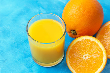 Orange fresh drink, glass of juice and ripe citrus fruits on a blue background