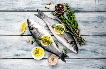 Fresh fish sea bass. Sea bass raw fish with ingredients spices and herbs on wooden background