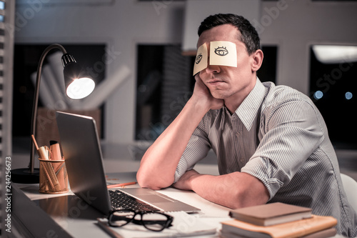 Fotomural Pleasant tired man sitting at the table in the office
