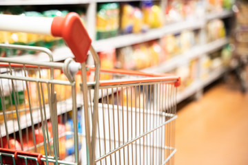 Shopping trolley cart with shallow DOF against supermarket aisle background