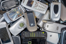A Pile Of Old Cell Phones To Be Recycled. There Are A Variety Of Phones, But Most Are The Flip To Open Type. The Phones Are Dirty. Branding Was Removed.