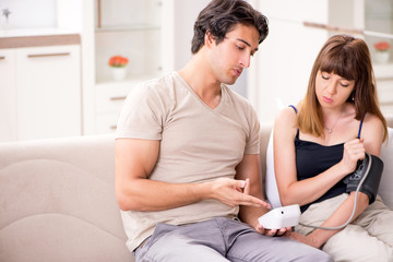 Husband checking wife's blood pressure