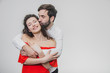 © Andrii - A young, handsome young man kisses his beautiful girl in a cheek gently. Embracing her. During this girl dressed in a red dress, a guy in a white shirt.