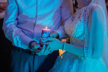 bride and groom hold a candle together