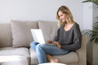 canvas print picture - Junge Frau mit Laptop sitzt auf einem Sofa