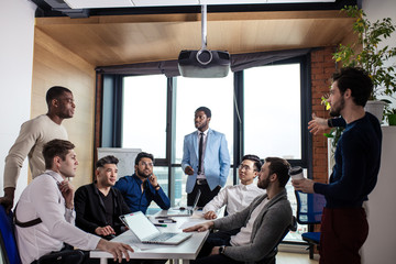 Canvas Print - Businessman in blue formal suit standing and leading business meeting. Male chief executive putting his ideas during presentation in boardroom.