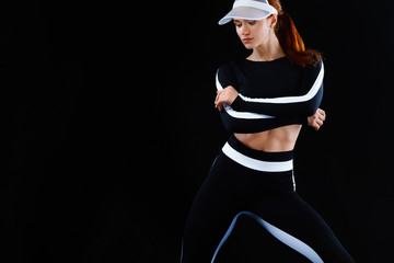 Wall Mural - Strong athletic woman , posing on black background wearing in sportswear. Energy fitness and sport motivation. Copy space.