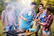 © NDABCREATIVITY - Happy friends enjoying barbecue party in forest
