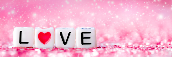 Wall Mural - White Beads With Word Love And Red Heart Shape On Shiny Pink Glittering Background - Valentine's Day Concept