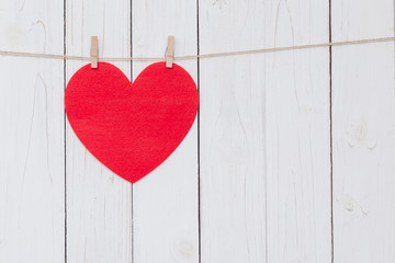 Wall Mural - Red heart hanging on white wood  background with copy space.