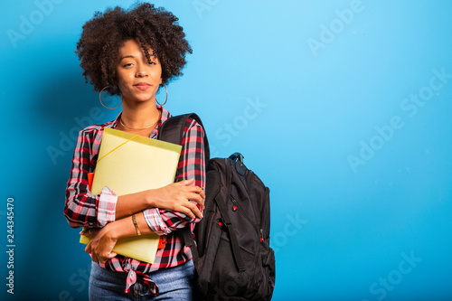Fotomural young african student with backpack on the back on blue background