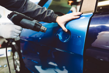 Wall Mural - Car wrapping specialist putting vinyl foil or film on car. Selective focus.