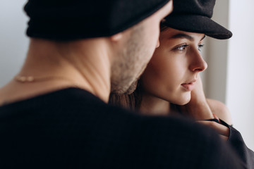 Wall Mural - Two hipster models: a man and a woman in a blank black t-shirt, jeans and posing. in a black hat, cap, love, kisses