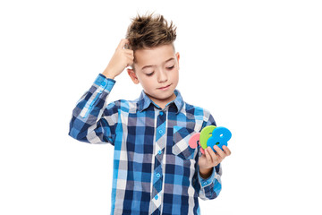 Cute boy with dyscalculia holding large colorful numbers and scratching his head. Learning disability concept on white background.