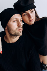 Wall Mural - Two hipster models: a man and a woman in a blank black t-shirt, jeans and posing. in a black hat, cap, love, kisses