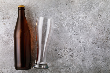 Full bottle of beer and empty glass on the table with copy space, top view