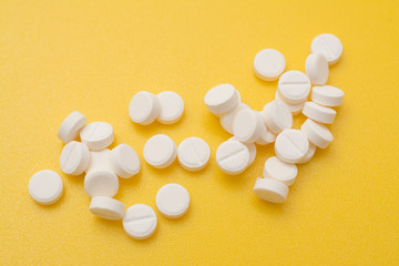 White pills aspirin or painkiller on yellow background, medical abstract