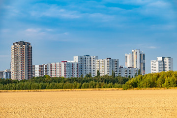 View over a harvested field to the satellite city Gropiusstadt in Berlin-Neukoelln illuminated by the sun.