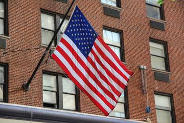 The flag of the United States or the star spangled banner waving on the rooftop of a fire brigade in New York city