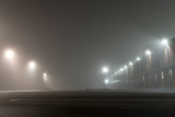 Fototapeta Na ścianę - Empty urban car parking and streetlights at foggy night. Old Industrial brick building and lanterns on lonely street