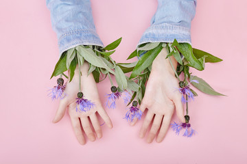 Wall Mural - Hands and spring flowers are on a pink table skincare. Nature Cosmetics for hand skin care, a means to reduce wrinkles on hands, moisturizing. Natural cosmetics from flower extract, beauty and fashion