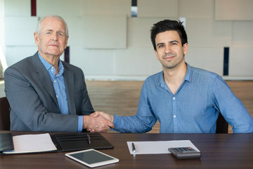 Wall Mural - Smiling businessmen shaking hands. Two satisfied partners making deal. Business agreement concept