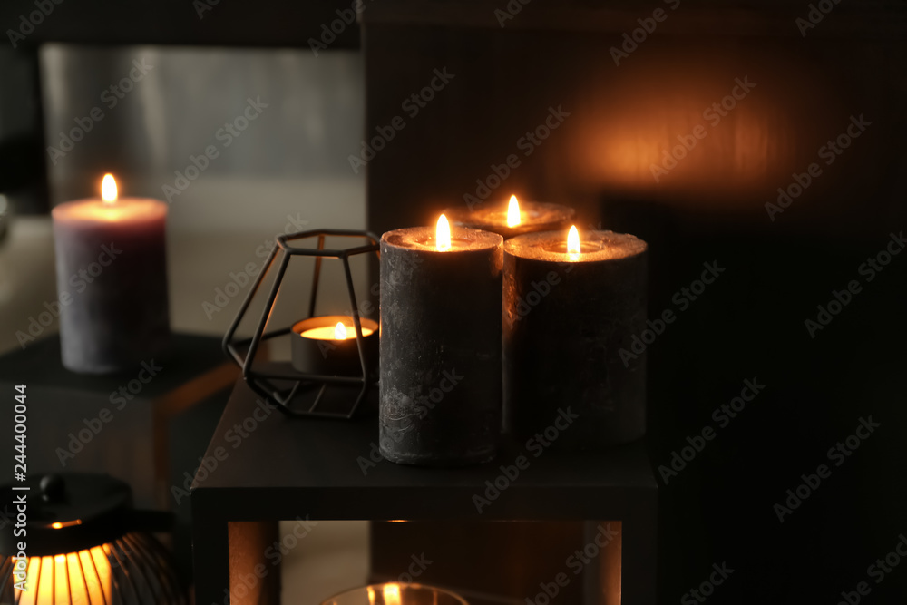 Beautiful burning candles on shelf in room