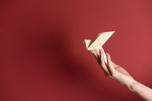 Female Hand With Origami Bird On Color Background