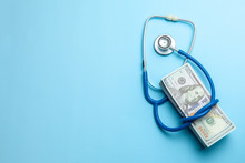 Stack Of Cash Dollars And Stethoscope On Blue Background. The Concept Of Medical Strechevka Or Expensive Medicine, Doctors Salary. Copy Space For Text.
