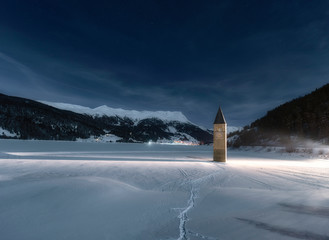 Wall Mural - wintery scene - frozen lake with sunken church tower under star-speckled sky