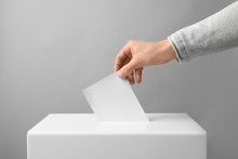 Man Putting His Vote Into Ballot Box On Light Background, Closeup