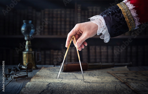 The captain of the old ship paves the course with the help of vintage maps an...