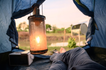 Wall Mural - View from inside of tent with relaxing and campfire near swamp in evening