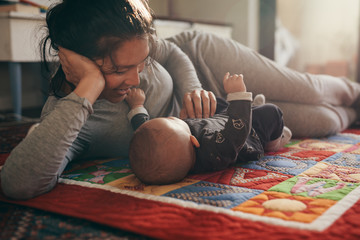 Wall Mural - Mother lying on bed with her baby