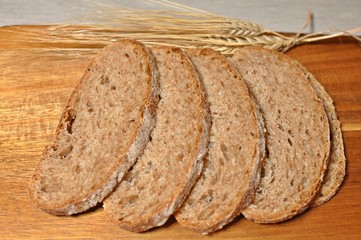 Top table of slices of maroon cereal healthy homemade bread with dried wheat decoration on wooden table background