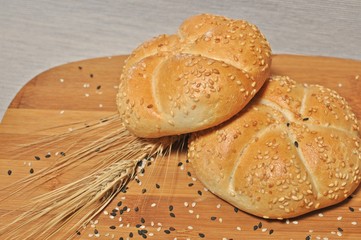 Top table with two fresh backed buns with wheat and sesame ornament on wooden plate