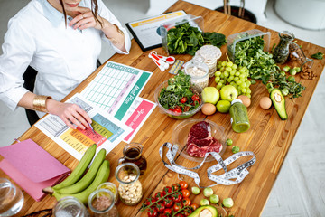 Wall Mural - Dietitian writing a diet plan, view from above on the table with different healthy products and drawings on the topic of healthy eating