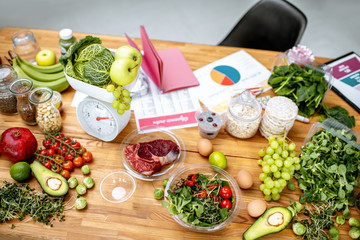 Wall Mural - Nutritionists working place with variety of healthy raw food, weights and documents on a topic of healthy food on the table