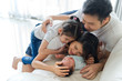© Kawee - Happy family at home. Asian father, mother and sister on sofa are smiling, laughing and playing with newborn baby, new member of their family. They spent a great time together. Happy family concept.