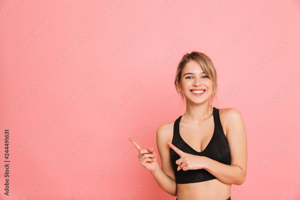 Young sports blonde woman make fitness exercises isolated posing pointing. - obrazy, fototapety, plakaty 