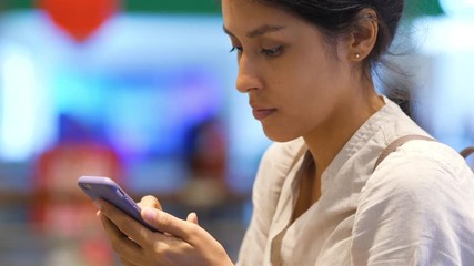 Portrait of Young Mixed Race Woman Using Smartphone in Airport. Female Scrolling Photos on Mobile Phone. 4K Slowmotion Closeup.