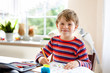 © Irina Schmidt - Happy smiling little kid boy at home making homework at the morning before the school starts. Little child doing excercise, indoors. Elementary school and education: Boy drawing geometric figures