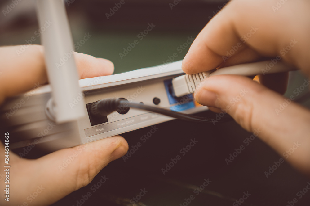 Internet Router Man Man plugging internet cable into wifi router. Stock Photo | Adobe Stock