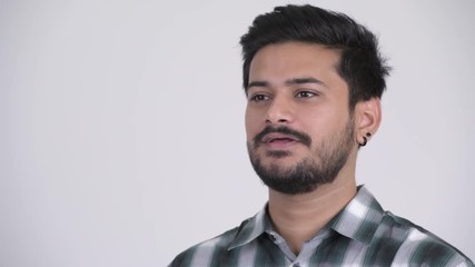 Wall Mural - Young handsome bearded Indian man thinking while talking