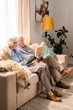 © Seventyfour - Wide angle portrait of happy senior couple with dog sitting on couch together and enjoying retirement