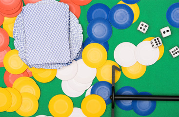 Wall Mural - top view of green poker table with multicolored chips, playing cards, dices and stick