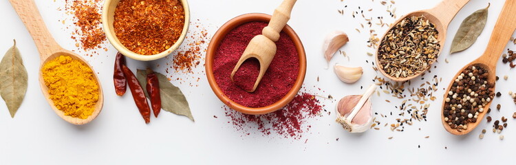 Assorted indian spices in bowls and spoons on white