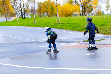 Two teenagers went down the roller coaster. Rear view. Young pair of roller skates outdoors in the Park