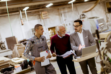 Wall Mural - Three men standing and discuss in furniture factory