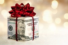 Christmas Present With Red Bow Wrapped In Dollar Banknotes